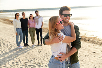 Image showing happy couple and group of friends on summer beach