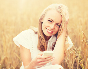 Image showing happy young woman with smartphone on cereal field