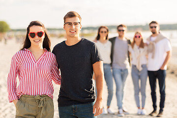 Image showing happy friends walking along summer beach