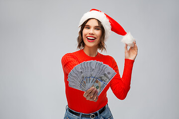 Image showing happy woman in santa hat with money on christmas