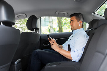 Image showing passenger with earphones and cellphone in taxi car