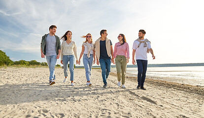 Image showing happy friends walking along summer beach