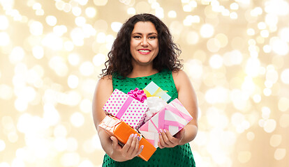Image showing happy woman holding gift boxes over lights