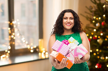 Image showing happy woman holding gifts over christmas tree