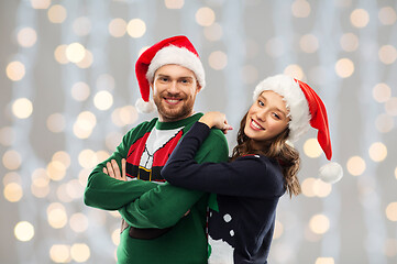 Image showing happy couple in christmas sweaters and santa hats