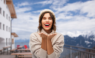 Image showing woman in winter hat sending air kiss at ski resort