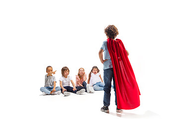 Image showing Child pretending to be a superhero with his friends sitting around