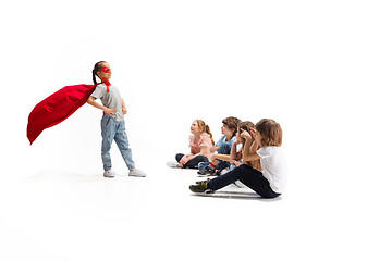 Image showing Child pretending to be a superhero with her friends sitting around