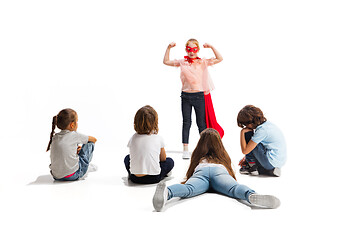 Image showing Child pretending to be a superhero with her friends sitting around