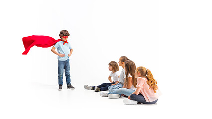 Image showing Child pretending to be a superhero with his friends sitting around