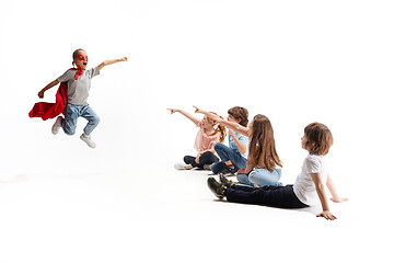 Image showing Child pretending to be a superhero with her friends sitting around