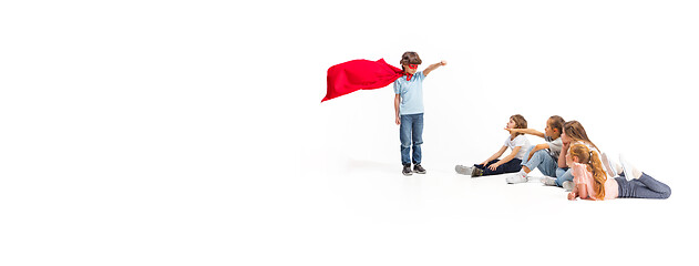 Image showing Child pretending to be a superhero with his friends sitting around