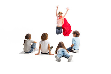 Image showing Child pretending to be a superhero with her friends sitting around