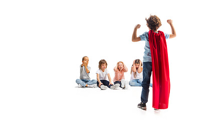 Image showing Child pretending to be a superhero with his friends sitting around