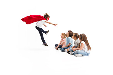 Image showing Child pretending to be a superhero with his friends sitting around