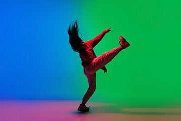 Image showing Stylish sportive girl dancing hip-hop in stylish clothes on colorful background at dance hall in neon light. Youth culture, movement, style and fashion, action.