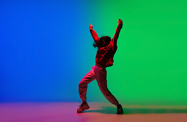 Image showing Stylish sportive girl dancing hip-hop in stylish clothes on colorful background at dance hall in neon light. Youth culture, movement, style and fashion, action.