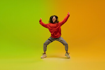 Image showing Stylish sportive girl dancing hip-hop in stylish clothes on colorful background at dance hall in neon light. Youth culture, movement, style and fashion, action.