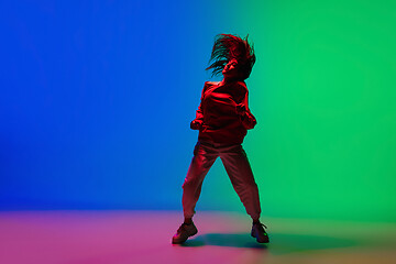 Image showing Stylish sportive girl dancing hip-hop in stylish clothes on colorful background at dance hall in neon light. Youth culture, movement, style and fashion, action.