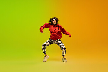 Image showing Stylish sportive girl dancing hip-hop in stylish clothes on colorful background at dance hall in neon light. Youth culture, movement, style and fashion, action.