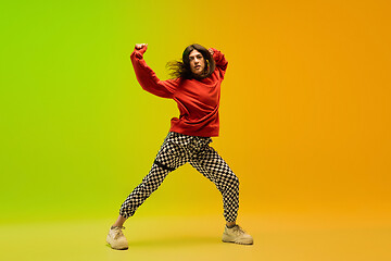 Image showing Stylish sportive girl dancing hip-hop in stylish clothes on colorful background at dance hall in neon light. Youth culture, movement, style and fashion, action.