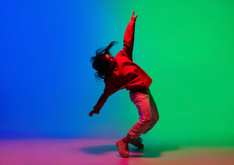 Image showing Stylish sportive girl dancing hip-hop in stylish clothes on colorful background at dance hall in neon light. Youth culture, movement, style and fashion, action.