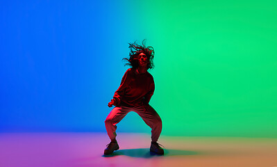 Image showing Stylish sportive girl dancing hip-hop in stylish clothes on colorful background at dance hall in neon light. Youth culture, movement, style and fashion, action.