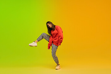 Image showing Stylish sportive girl dancing hip-hop in stylish clothes on colorful background at dance hall in neon light. Youth culture, movement, style and fashion, action.