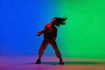 Image showing Stylish sportive girl dancing hip-hop in stylish clothes on colorful background at dance hall in neon light. Youth culture, movement, style and fashion, action.