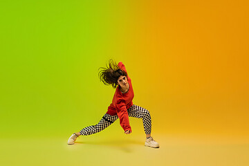 Image showing Stylish sportive girl dancing hip-hop in stylish clothes on colorful background at dance hall in neon light. Youth culture, movement, style and fashion, action.