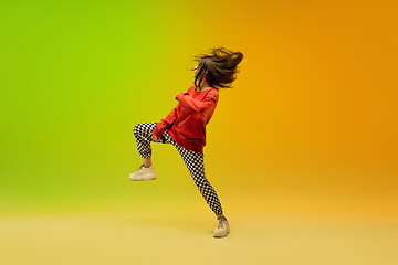 Image showing Stylish sportive girl dancing hip-hop in stylish clothes on colorful background at dance hall in neon light. Youth culture, movement, style and fashion, action.