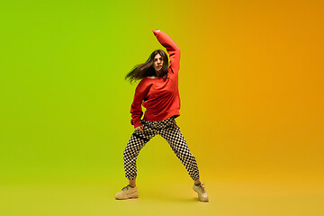 Image showing Stylish sportive girl dancing hip-hop in stylish clothes on colorful background at dance hall in neon light. Youth culture, movement, style and fashion, action.