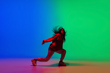 Image showing Stylish sportive girl dancing hip-hop in stylish clothes on colorful background at dance hall in neon light. Youth culture, movement, style and fashion, action.