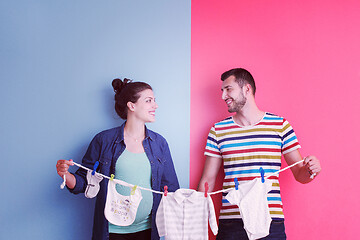 Image showing young couple holding baby bodysuits