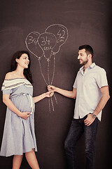 Image showing pregnant couple drawing their imaginations on chalk board