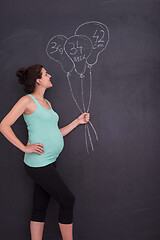 Image showing Portrait of pregnant woman in front of black chalkboard