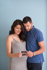 Image showing couple looking ultrasound picture isolated on blue background