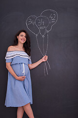 Image showing Portrait of pregnant woman in front of black chalkboard