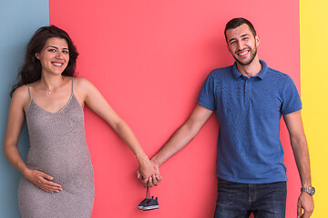 Image showing young happy couple holding newborn baby shoes