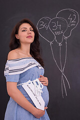 Image showing Portrait of pregnant woman in front of black chalkboard