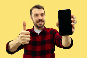 Image showing Half-length close up portrait of young man on yellow background.