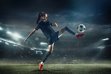 Image showing Female soccer player kicking ball at the stadium