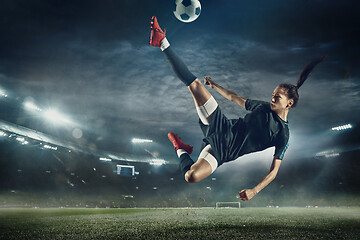 Image showing Female soccer player kicking ball at the stadium