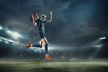 Image showing Female soccer player kicking ball at the stadium