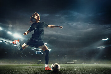 Image showing Female soccer player kicking ball at the stadium