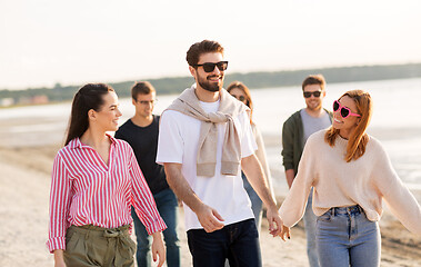 Image showing happy friends walking along summer beach