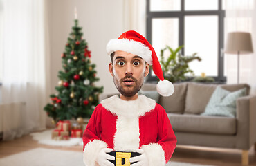 Image showing surprised man in santa costume over christmas tree