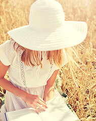 Image showing close up of woman reading book on cereal field