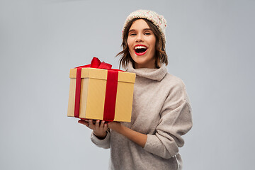 Image showing young woman in knitted winter hat holding gift box