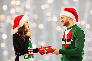 Image showing happy couple in christmas sweaters with gift box